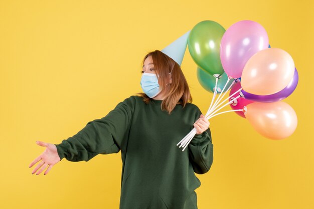 Vue de face jeune femme tenant des ballons colorés