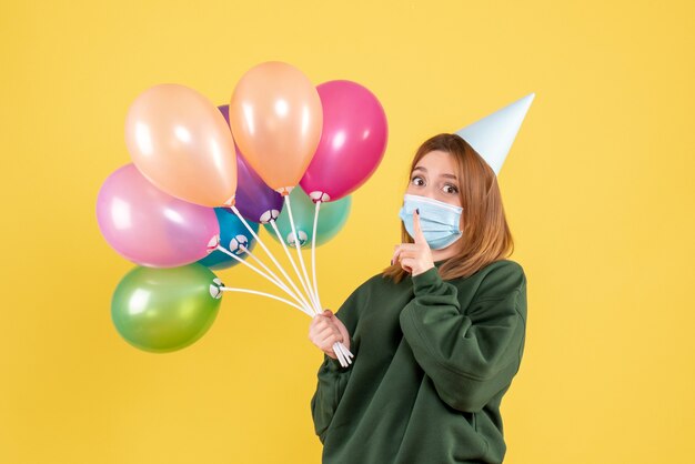 Vue de face jeune femme tenant des ballons colorés