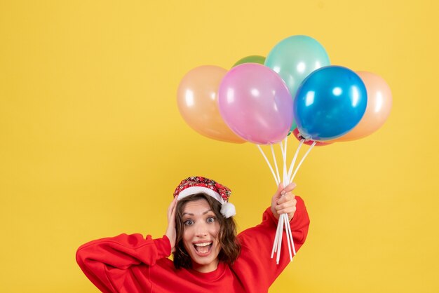 Vue de face jeune femme tenant des ballons sur jaune