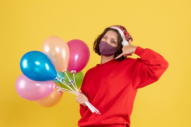 Vue de face jeune femme tenant des ballons en masque sur fête de célébration jaune