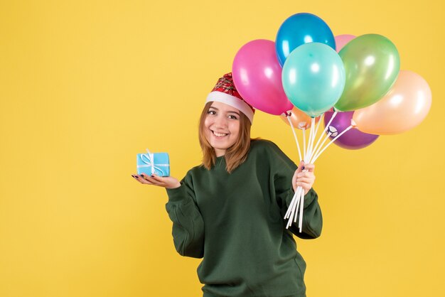 Vue de face jeune femme tenant des ballons et peu de cadeau