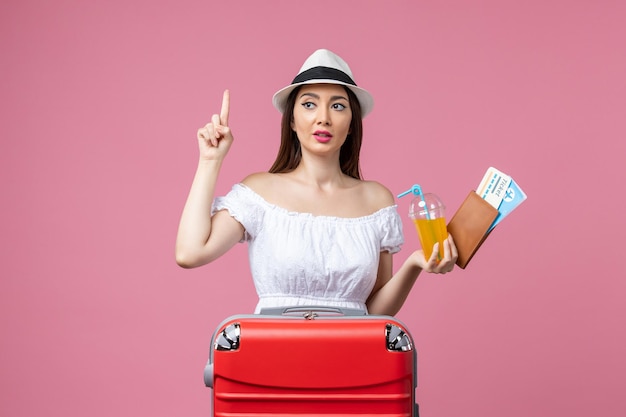 Vue de face jeune femme tenant des billets d'avion pour des vacances sur le mur rose voyage d'été émotion voyage en avion