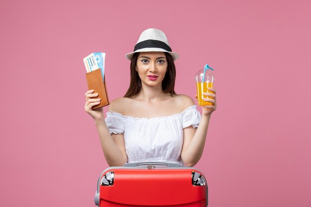 Vue de face jeune femme tenant des billets et un cocktail en vacances d'été sur le mur rose voyage vacances été voyage couleur chaleur