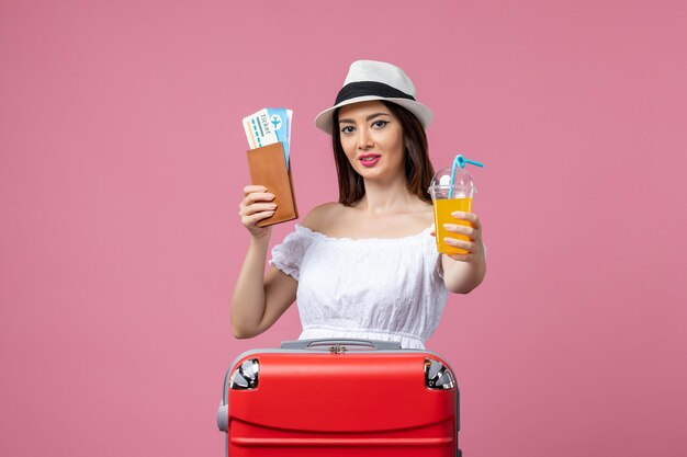 Vue de face jeune femme tenant des billets et un cocktail en vacances d'été sur le sol rose voyage vacances été voyage couleur chaleur