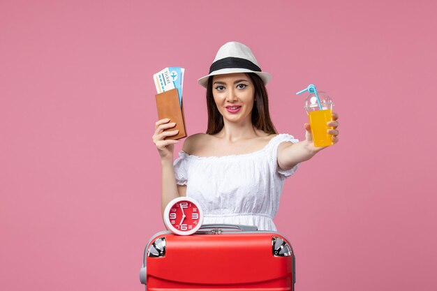 Vue de face jeune femme tenant des billets et un cocktail en vacances sur le mur rose voyage femme vacances voyage été chaleur