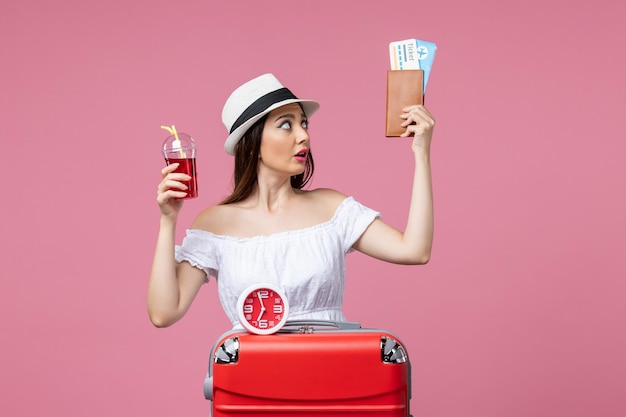 Vue de face jeune femme tenant des billets et du jus en vacances sur le bureau rose voyage voyage femme d'été