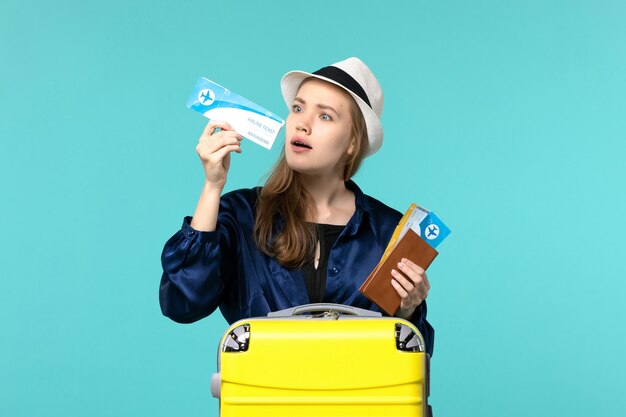 Vue de face jeune femme tenant des billets et la préparation pour les vacances sur fond bleu voyage voyage vacances en avion de mer