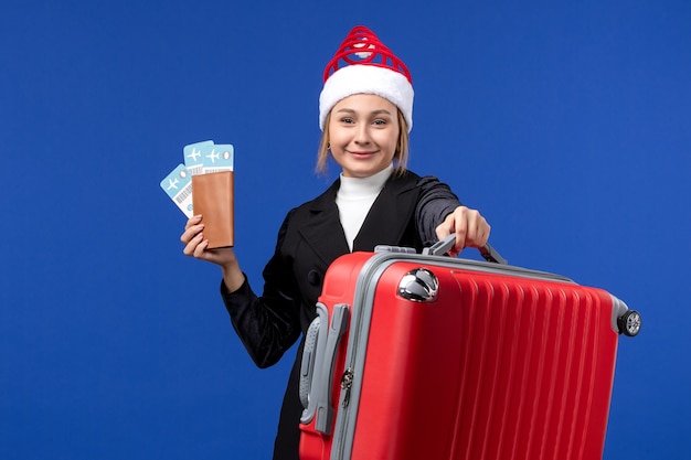 Vue de face jeune femme tenant des billets avec sac sur fond bleu vacances avion vacances