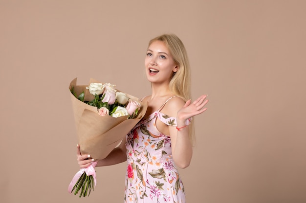 Vue De Face D'une Jeune Femme Tenant Un Bouquet De Belles Roses Sur Un Mur Marron