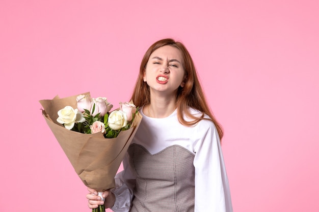 Vue de face jeune femme tenant un bouquet de belles roses sur rose