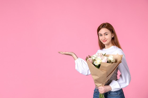 Vue de face jeune femme tenant un bouquet de belles roses sur rose