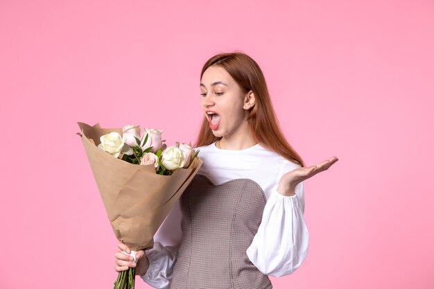 Vue de face jeune femme tenant un bouquet de belles roses sur des roses