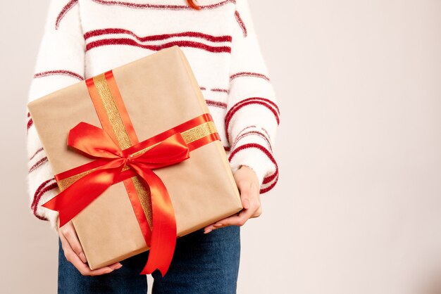 Vue de face de la jeune femme tenant un cadeau de Noël sur un mur blanc