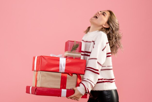 Vue de face jeune femme tenant des cadeaux de Noël