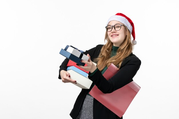 Vue de face jeune femme tenant des cadeaux de vacances sur mur blanc cadeau Noël nouvel an