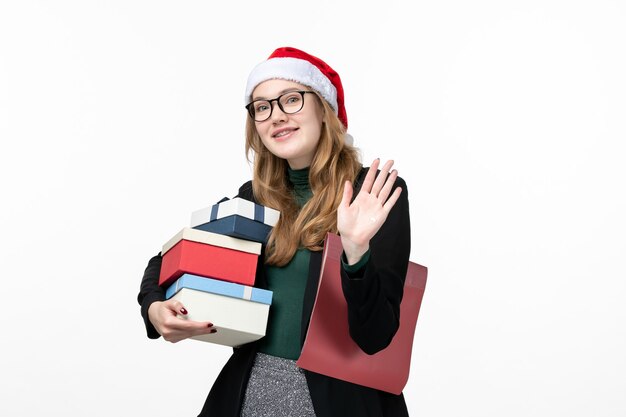 Vue de face jeune femme tenant des cadeaux de vacances sur le mur blanc livre leçon college