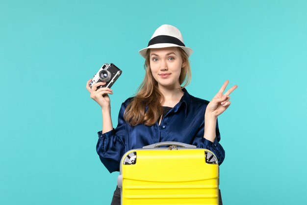 Vue de face jeune femme tenant la caméra sur le fond bleu femme voyage avion de voyage en mer