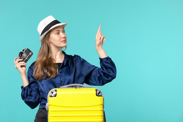 Vue de face jeune femme tenant la caméra et souriant sur fond bleu clair femme voyage mer voyage avion