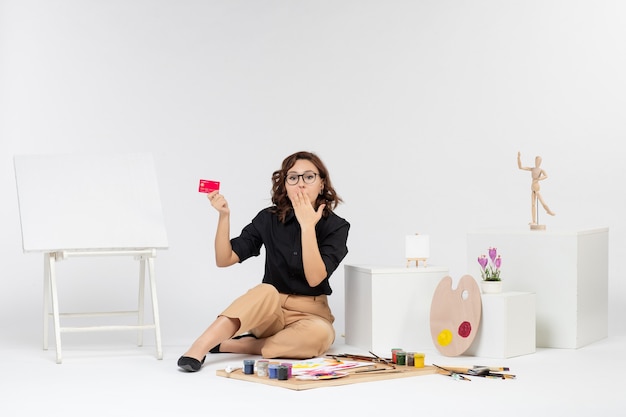 Vue de face jeune femme tenant une carte bancaire sur fond blanc