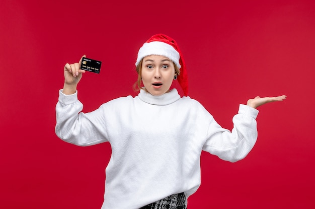 Vue de face jeune femme tenant une carte bancaire sur fond rouge