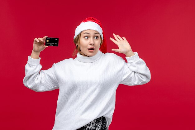 Vue de face jeune femme tenant une carte bancaire sur fond rouge