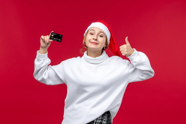 Vue de face jeune femme tenant une carte bancaire sur fond rouge