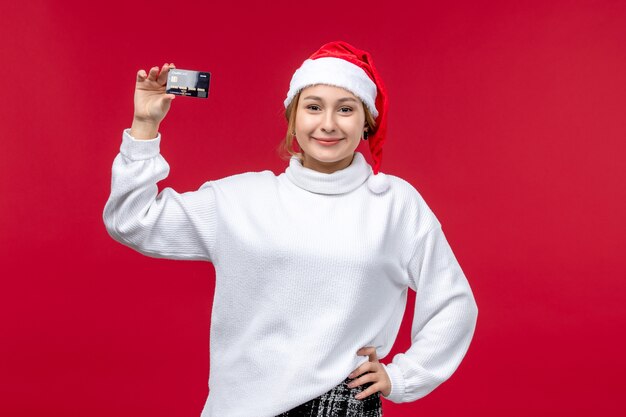 Vue de face jeune femme tenant une carte bancaire sur fond rouge