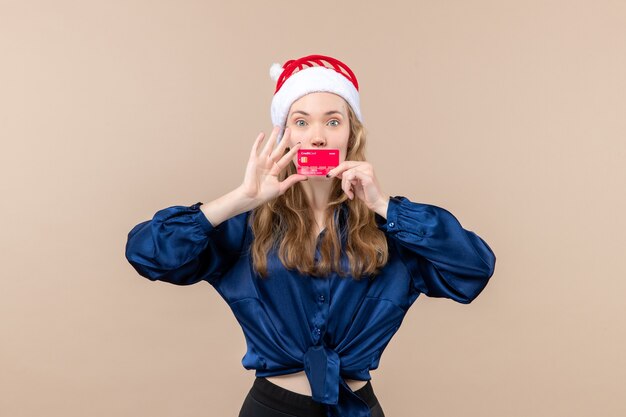 Vue de face jeune femme tenant une carte bancaire rouge sur plancher rose vacances argent de Noël photo nouvel an émotion