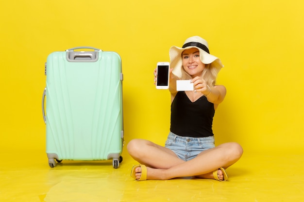 Vue de face jeune femme tenant une carte blanche et téléphone