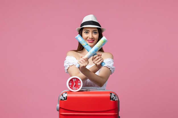 Vue de face jeune femme tenant des cartes papier en vacances sur mur rose voyage voyage été chaleur femme vacances
