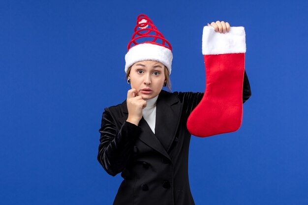 Vue de face jeune femme tenant la chaussette de Noël sur mur bleu clair vacances nouvel an humain