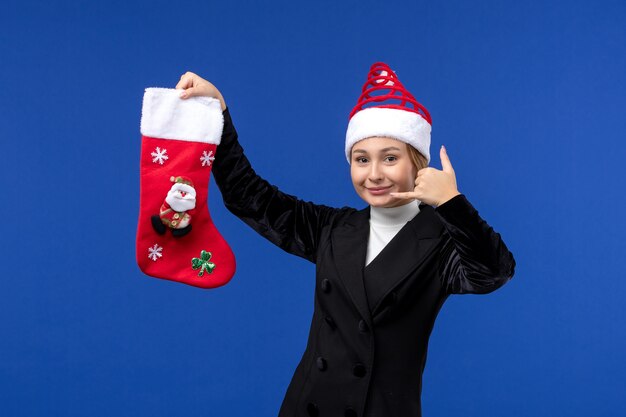 Vue de face jeune femme tenant la chaussette de Noël sur le mur bleu vacances femme nouvel an