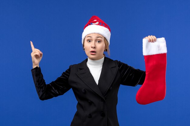 Photo gratuite vue de face jeune femme tenant chaussette de noël rouge sur mur bleu vacances du nouvel an humain