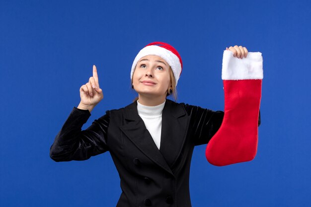 Vue de face jeune femme tenant une chaussette de Noël rouge sur le mur bleu vacances humaines nouvel an