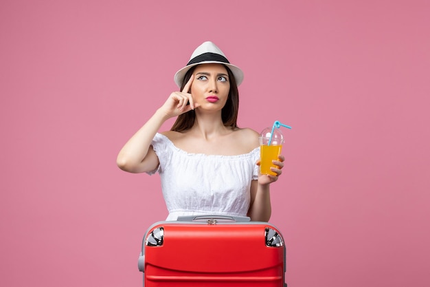 Vue de face jeune femme tenant un cocktail en vacances d'été sur le mur rose vacances chaleur voyage voyage d'été