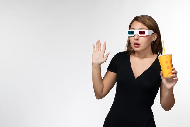 Vue de face jeune femme tenant du soda dans des lunettes de soleil sur une surface blanche