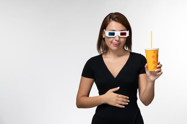 Vue de face jeune femme tenant du soda dans des lunettes de soleil sur une surface blanche