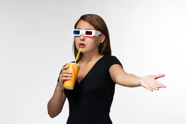 Vue de face jeune femme tenant du soda dans des lunettes de soleil sur une surface blanche