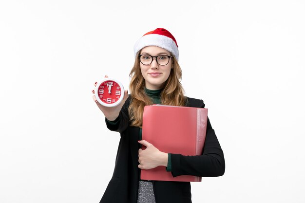 Vue de face jeune femme tenant des fichiers et de l'horloge sur le livre de Noël du nouvel an plancher blanc