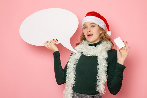 Vue de face jeune femme tenant grand panneau blanc et carte bancaire sur le modèle de mur rose vacances Noël nouvel an couleurs émotion
