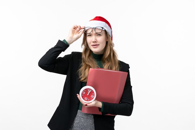 Vue de face jeune femme tenant l'horloge et les fichiers sur le sol blanc livre leçon collège