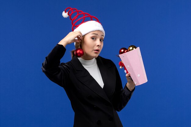 Vue de face jeune femme tenant des jouets d'arbre sur le bureau bleu bleu vacances de nouvel an
