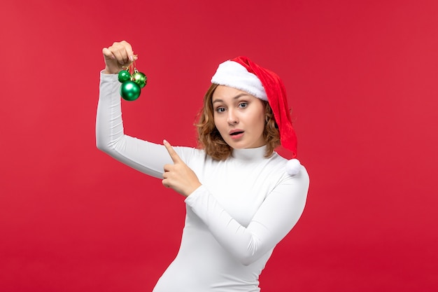 Vue de face de la jeune femme tenant des jouets de Noël sur rouge