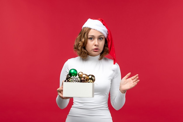 Vue de face de la jeune femme tenant des jouets de Noël sur rouge