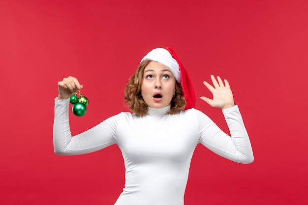 Vue de face de la jeune femme tenant des jouets de Noël sur rouge