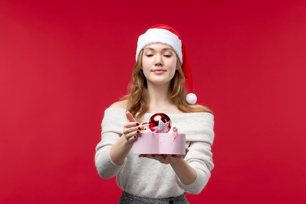 Vue de face de la jeune femme tenant des jouets de Noël sur rouge