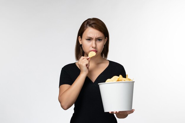 Vue de face jeune femme tenant le panier avec des croustilles sur un bureau blanc