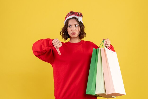 Vue de face jeune femme tenant des paquets de shopping sur jaune