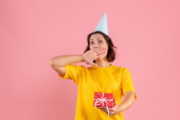 Vue de face de la jeune femme tenant peu de cadeau sur le mur rose