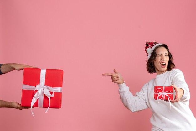 Vue de face de la jeune femme tenant peu de cadeau sur le mur rose